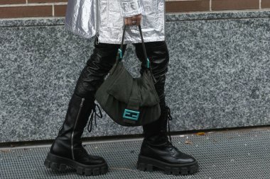 Milan, İtalya - 22 Eylül 2021: Sokak tarzı kıyafet, siyah deri pantolon giyen şık kadın, siyah parlak deri çizmeler, bilek bağları, Milan, İtalya sokaklarında Fendi 'nin mavi renkli el çantalı koyu yeşil bir kumaş..