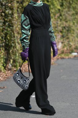 Milan, İtalya - 24 Eylül 2021: Sokak tarzı kıyafet, siyah bir Prada bluz, siyah pantolon, mor uzun eldivenler ve İtalya 'nın Milano sokaklarında Prada çanta giyen şık kadın.
