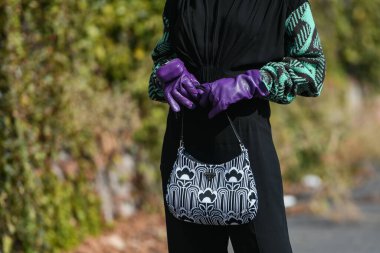 Milan, İtalya - 24 Eylül 2021: Sokak tarzı kıyafet, siyah bir Prada bluz, siyah pantolon, mor uzun eldivenler ve İtalya 'nın Milano sokaklarında Prada çanta giyen şık kadın.