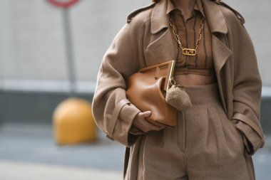 Milan, İtalya - 22 Eylül 2021: Sokak tarzı kıyafet, Fendi 'den altın büyük kolye takan şık bir kadın, Fendi' den altın zincirli bir FF kolye, siyah çizgili kahverengi ve FF monogramlı kesilmiş gömlek, bej balon h