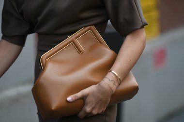 Milan, İtalya - 22 Eylül 2021: Sokak tarzı kıyafet, Fendi 'den altın bir zincir FF kolye takan şık kadın, kahverengi kabarık kısa kollu, kemerli midi tüp elbise, kahverengi, parlak deri Fendi çanta, kahverengi deri topuklu Fendi klular.