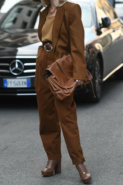 Milan, İtalya - 22 Eylül 2021: Sokak tarzı kıyafet, bej tişört giyen şık kadın, kahverengi ceket, büyük takım elbise pantolon ve Milano, İtalya sokaklarında kahverengi deri bir çanta.