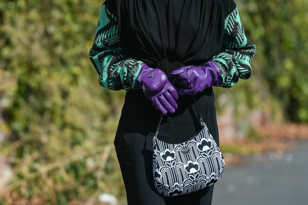 Milan, İtalya - 24 Eylül 2021: Sokak tarzı kıyafet, siyah bir Prada bluz, siyah pantolon, mor uzun eldivenler ve İtalya 'nın Milano sokaklarında Prada çanta giyen şık kadın.