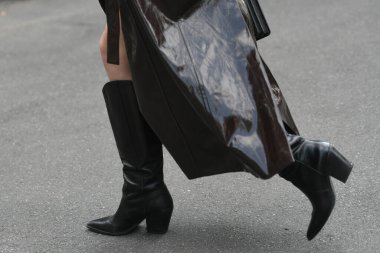 Sokak tarzı kıyafet. Parlak koyu kahverengi ceket giyen kadın. Siyah el çantası ve botlar.