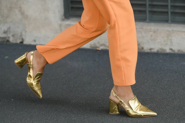 Street style outfit - woman wearing persian orange pants and golden shoes