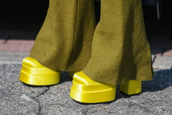 Street style outfit - woman wearing neon yellow platform shoes and mustard pants