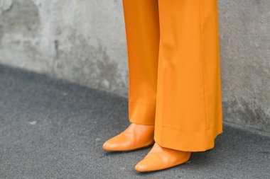 MILAN, ITALY - FEBRUARY 24, 2022: Woman wearing orange outfit: blazer jacket, pants and shoes.