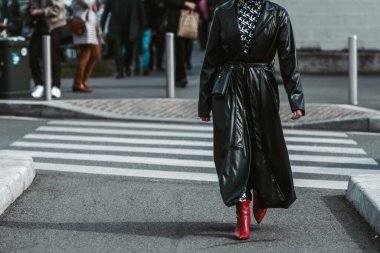 MILAN, ITALY - FEBRUARY 24: Street style outfit - woman wearing black leather skirt and red shoes.
