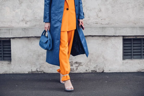 ミラノ イタリア 2月24日 ストリートスタイル 青い光沢のあるレザーロングコートを身に着けている女性 マッチングブルーハンドバッグ ネオンオレンジブレザージャケット ネオンオレンジのスーツパンツと淡いブルーのかかとのサンダルを一致させる — ストック写真