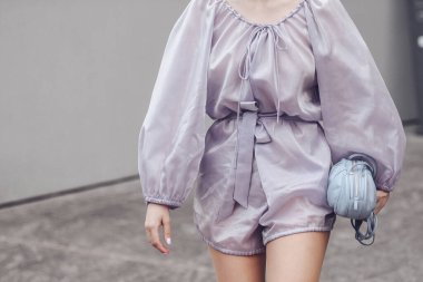 Milan, İtalya - Şubat, 24: sokak tarzı, mor tulumlu kadın, açık mor omuz çantası, beyaz parlak deri timsah yüksek çizmeleri.