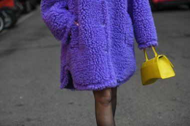Milan, Italy - February, 24: Street style, woman wearing a furry purple coat, yellow bag and purple sandals.. clipart