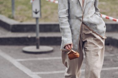 Milan, İtalya - Şubat, 24: sokak tarzı, gümüş ceketli kadın, bej rengi pantolon, kahverengi deri bir mikro çanta Fendi 'den ilk çanta, büyük gümüş tokalı topuklu beyaz deri.