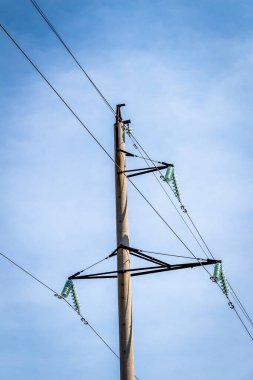 Mavi gökyüzüne karşı yüksek voltajlı elektrik hatları ve ekipmanlar.