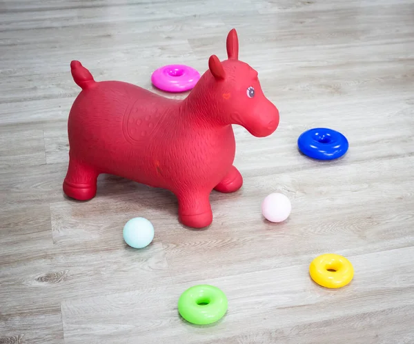 おもちゃの間の部屋の床には赤いプラスチック製の馬が立っている — ストック写真