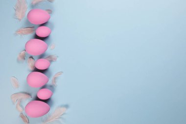 Mavi arka planda pembe Paskalya yumurtaları ve metin için yeri olan tüyler.