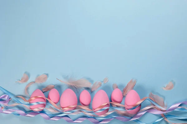 Huevos Pascua Rosados Sobre Fondo Azul Con Cintas Plumas Con Imagen de archivo