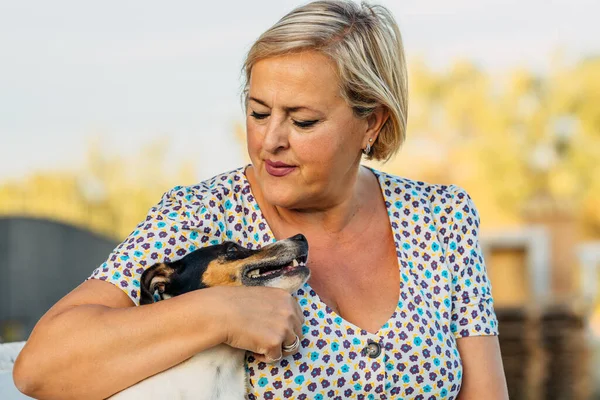 Närbild av en kvinna kramar en liten gammal hund utomhus — Stockfoto