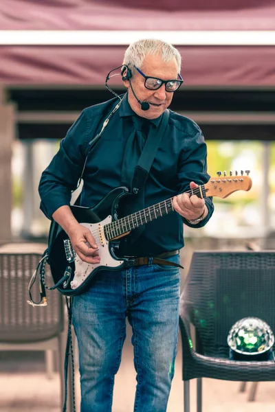 Pionowa przestrzeń fotograficzna starego muzyka grającego na gitarze elektrycznej na zewnątrz — Zdjęcie stockowe