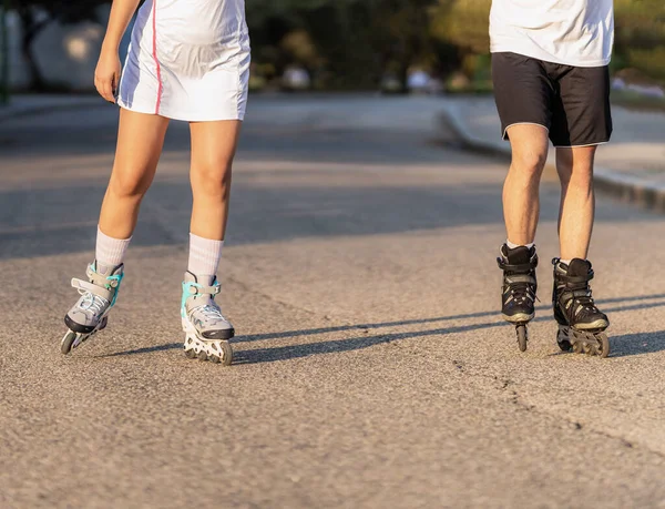 Cropped photo of the legs of two people on inline skates skating on a road — Stock Photo, Image