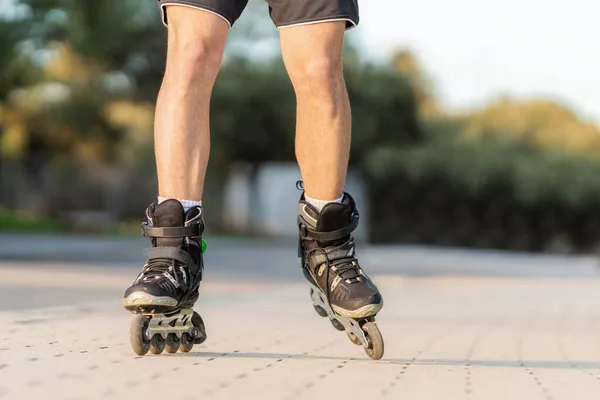 Male legs on black inline skates on a pedestrian street