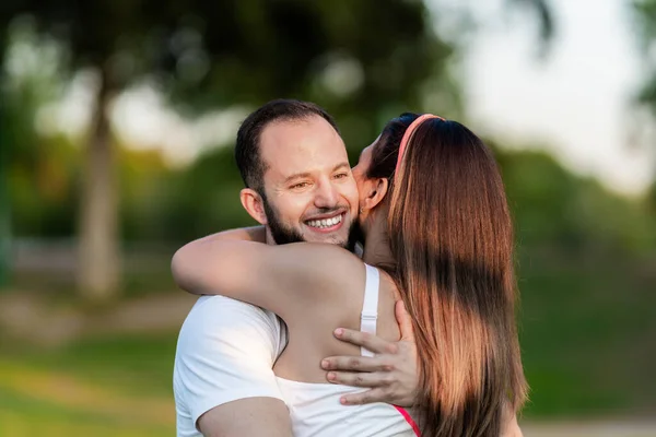 Uomo sorridente mentre abbraccia una donna in un parco — Foto Stock