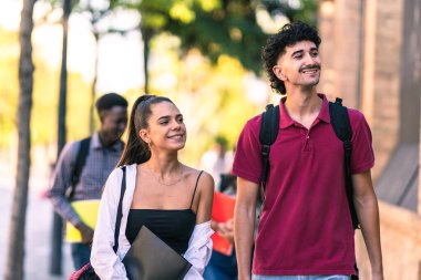 Farklı etnik kökenlere sahip bir grup öğrenci yazın sokakta yürüyor.