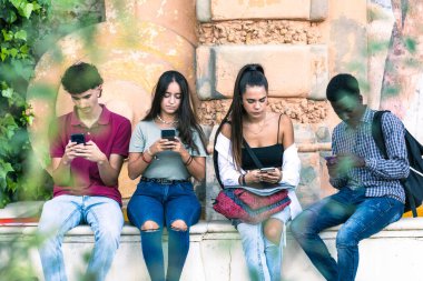 Cep telefonunu açık havada kullanan bir grup çok ırklı öğrencinin portresi.