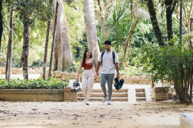 Ellerinde patenlerle parkta yürüyen Latin çift.