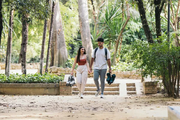 Ellerinde patenlerle parkta yürüyen Latin çift.