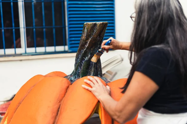 Женщина с помощью кисти нарисовала гигантскую фигуру тыквы из полистирола. — стоковое фото