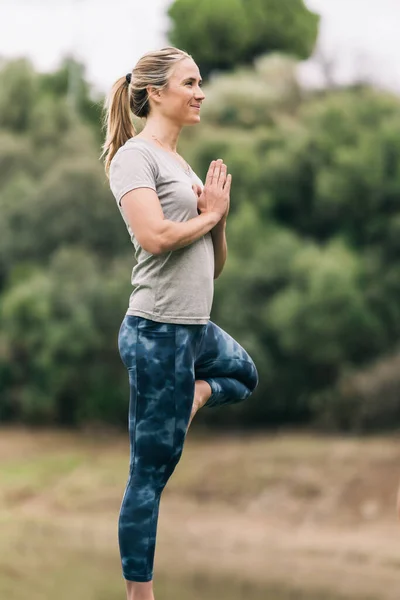 Vrouw staande doen yoga buiten midden in de natuur — Stockfoto