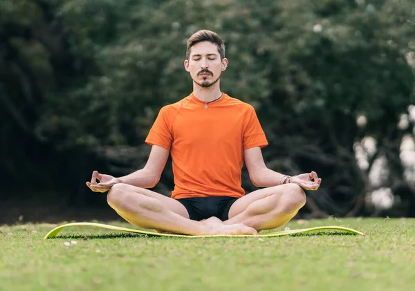 Man doet lotus yoga pose op een mat buiten — Stockfoto
