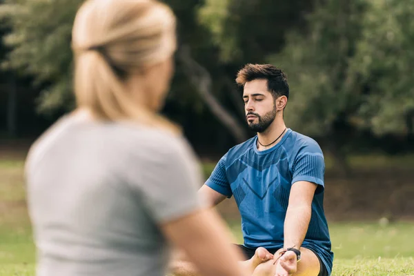 Leerling en instructeur doen yoga in een park — Stockfoto