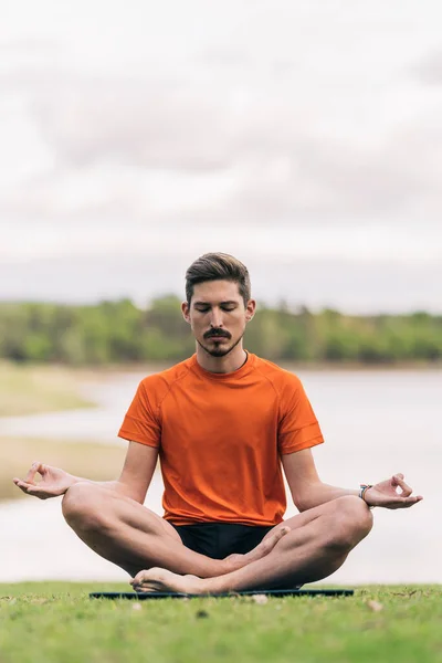 Man met een regenboog armband doet de lotus positie van yoga buiten — Stockfoto