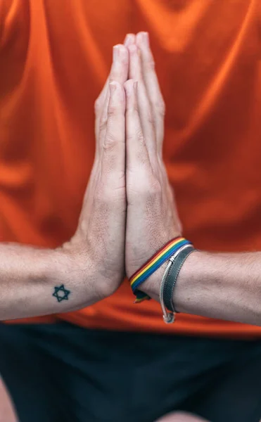 Handen van een man met een regenboog armband gebaren dankbaarheid doen yoga — Stockfoto