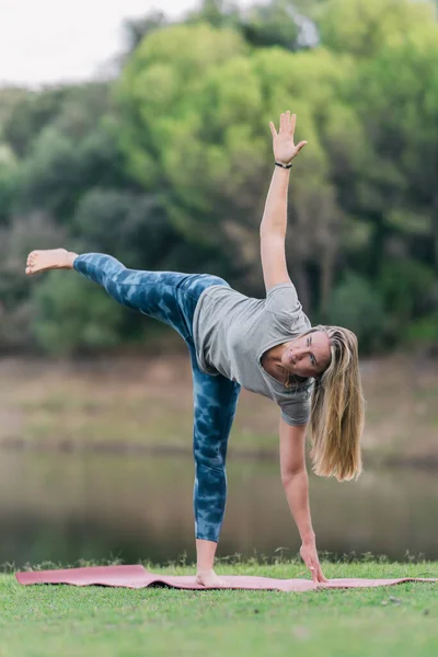 Женщина делает треугольную позу йоги в парке — стоковое фото
