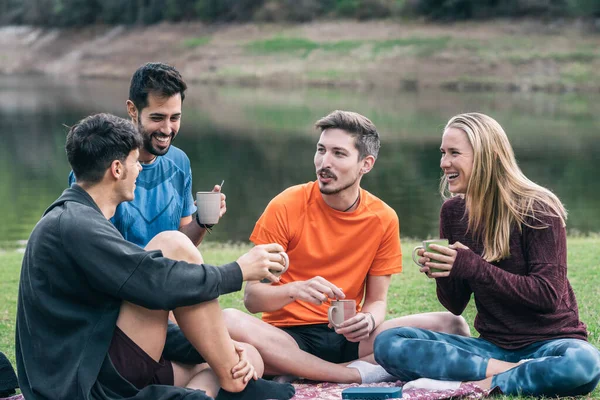 四个爱好运动的人坐在公园里喝茶，轻松自在地聊天 — 图库照片
