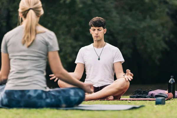 Man doet yoga boven een mat voor een instructeur buiten — Stockfoto