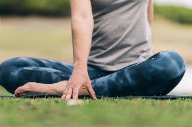 Kadınlar dışarıda yoga yaparken çimenlere dokunuyor.