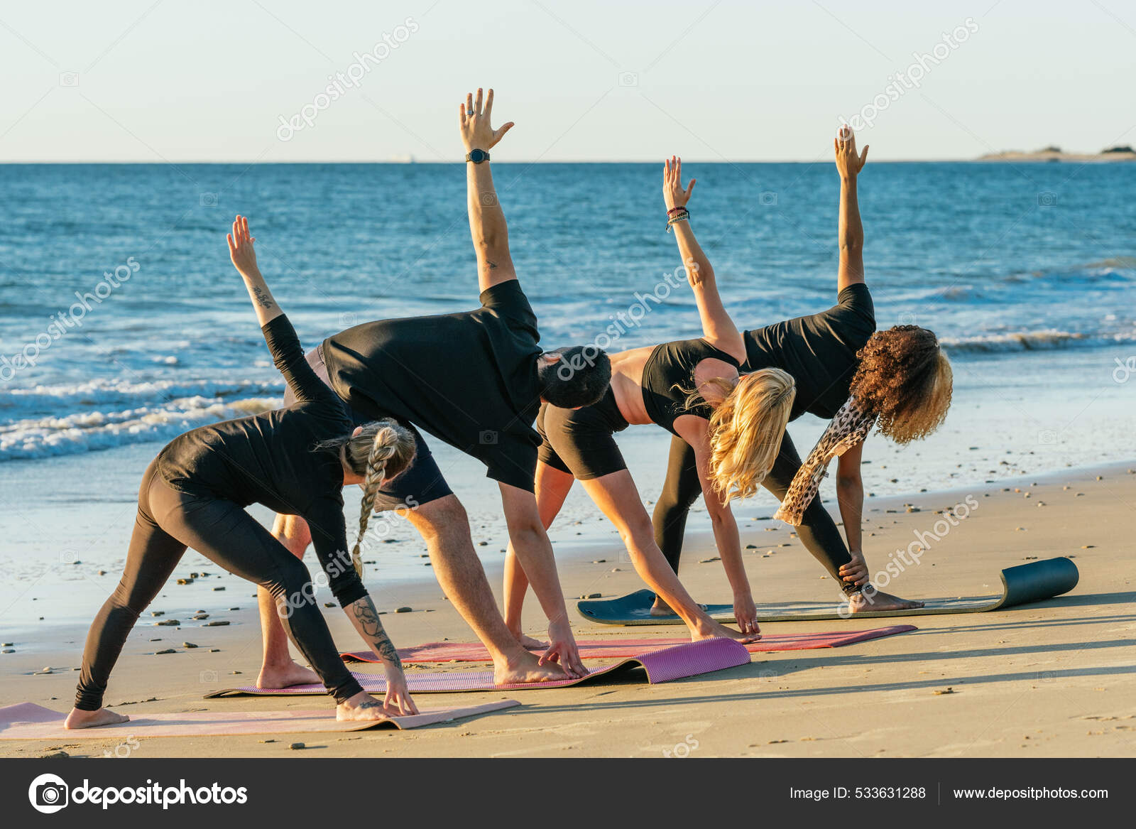 Pessoas de uma aula de ioga esticando as costas enquanto faz ioga na praia  fotos, imagens de © samuelperales #533631288