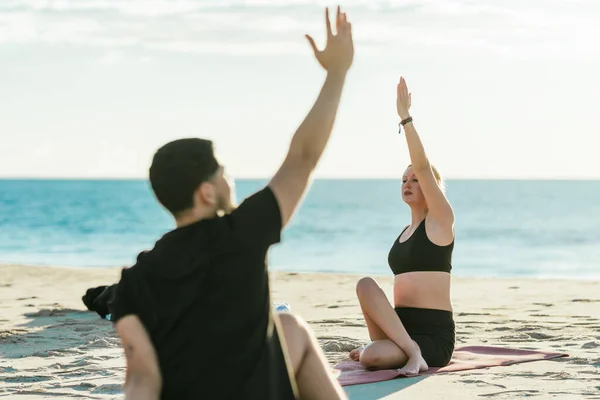 Yoga müteahhidi plajda bir adamla yoga yapıyor.