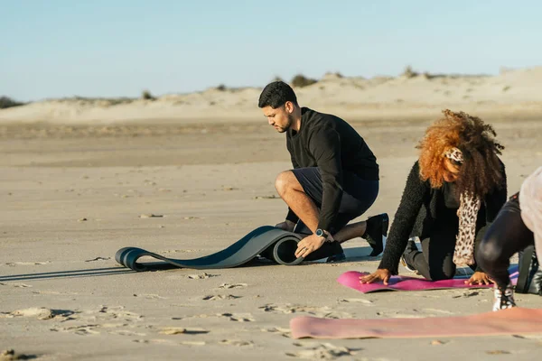 Два человека катают коврик для йоги на пляже — стоковое фото