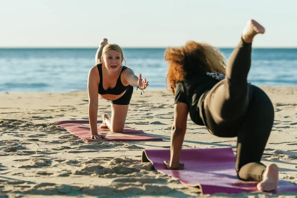 Тренер по йоге проводит частные занятия с беременной женщиной на пляже — стоковое фото