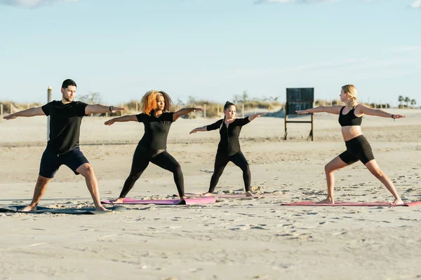 Учитель йоги проводит занятия с многонациональными людьми на пляже — стоковое фото