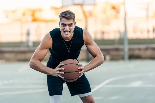 Uomo in posa con espressione aggressiva mentre tiene una pallacanestro all'aperto — Foto Stock