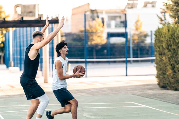 Due amici caucasici che giocano a basket in un campo all'aperto durante l'estate — Foto Stock