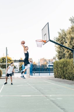 Arkadaşça bir basketbol maçında gol atan bir adamın dikey fotoğrafı.