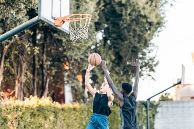 Arkadaşlar arasında oynanan bir maçta basket atmak için zıplayan kadın.