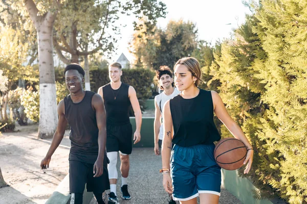 Quattro amici che camminano verso un sentiero con una palla da basket — Foto Stock