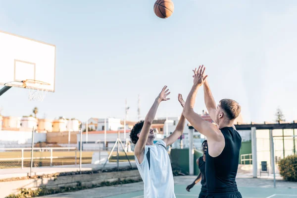 Tre persone che saltano per prendere la palla durante un calcio d'inizio in una partita di basket all'aperto — Foto Stock
